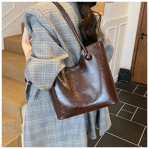 Detail van de karamelkleurige shopper tas van glanzend leer met ronde gespen en riemen