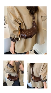 Détail du sac croissant froncé marron foncé avec pendentifs à glands perlés décoratifs