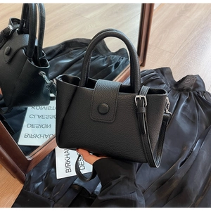 Detail of black pebbled leather bucket bag with retro round buckle and silver hardware