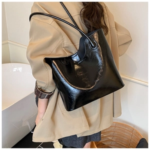 Detail van de zwarte tote bag van oliewasleer met glanzende afwerking en dunne riemen