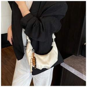 Vue détaillée d'un sac demi-lune crème orné de perles décoratives marron et blanches