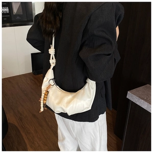 Détail du sac hobo avec bandoulière nouée et glands décoratifs en perles de bois