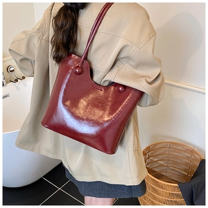 Detail van bordeauxrode leren shopper met unieke bolvormige gesp op de schouderband