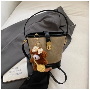 Detail view of khaki canvas bucket bag with black leather trim and cute bear charm