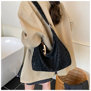 Detail of black leopard print hobo bag with beaded charm and wide fabric strap