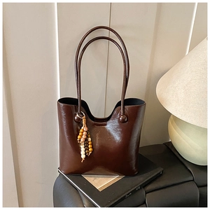 Detail van glanzende donkerbruine shopper met etnische kwast en lange handvaten