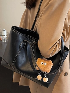 Sac cabas minimaliste en cuir noir avec surpiqûres blanches et pendentif en peluche