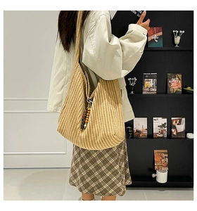 Detail of khaki ribbed knit bucket bag featuring a decorative wooden bead charm