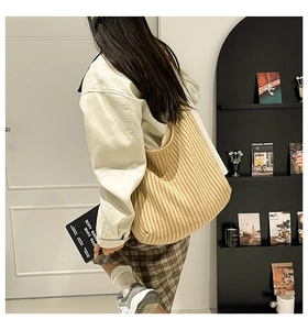 Detail of beige knitted hobo bag showing soft vertical stripe texture on a model