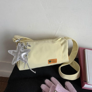 Large beige nylon gym bag with wide shoulder strap and silver star charm accessory