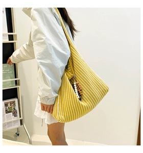 Detail of a large striped knit hobo bag featuring decorative dark wood beads on the side