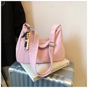 Pink leopard print tote bag with wide strap and colorful wooden beads on a suitcase