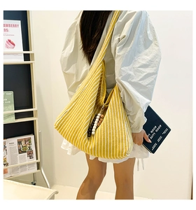 Detail of yellow striped knit tote bag with decorative wooden beads and woven shoulder strap