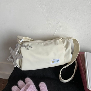 Detail of off-white nylon cylinder bag with star and balloon dog silver charms
