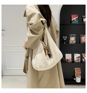 Detail of striped canvas hobo bag featuring decorative wood bead tassel and large capacity