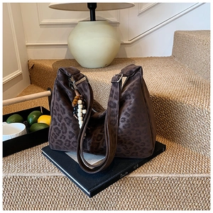 Close-up of leopard print hobo bag with bohemian bead charm and soft suede texture