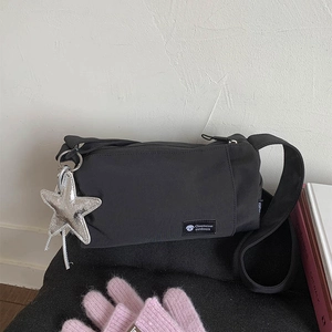 Detail of black crossbody pillow bag showing adjustable strap and silver star charm