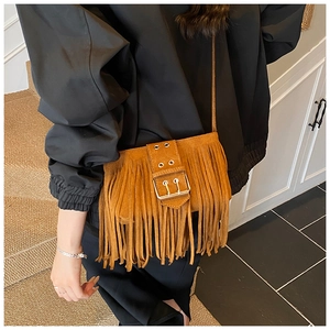 Gros plan d'un sac à bandoulière marron à franges avec une boucle carrée en métal doré