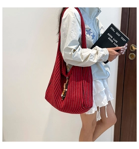 Detail of red and black striped knitted tote bag with bead charms shown on shoulder