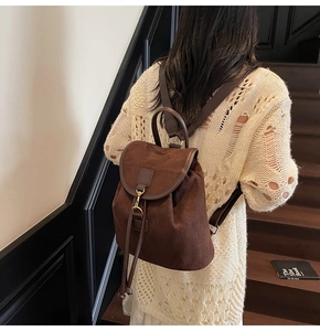 Deep coffee frosted faux suede backpack with flap and gold hook buckle on model back