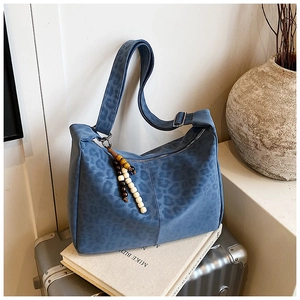 Detail of navy leopard print tote bag with a decorative wooden bead charm and zipper closure