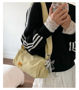 Detail of light yellow cylinder crossbody bag with cute silver bunny charm and orange label