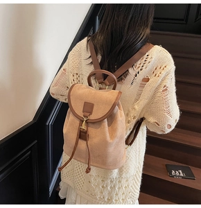Close-up of beige matte backpack with brown leather trim and metal hook on model