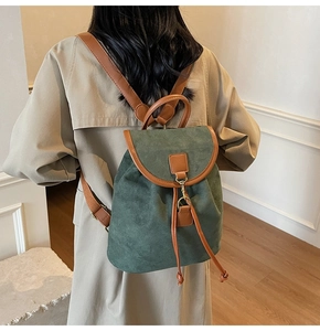 Deep green frosted backpack with brown leather straps worn by model in beige trench coat