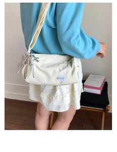 Close-up of off-white nylon crossbody bag with character patch and star charm accessory
