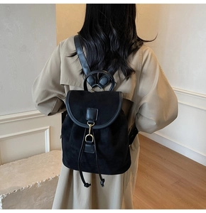Detail of black frosted leather backpack featuring a gold metal clasp and drawstring closure