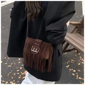 Détail d'un sac à bandoulière bohème en daim marron foncé avec de longues franges et boucle