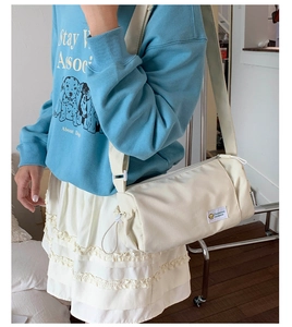 Detail of water-resistant off-white cylinder shoulder bag with adjustable strap