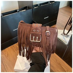 Détail d'un sac en daim marron foncé avec de longues franges et une boucle métallique