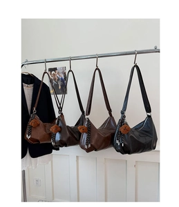 Macro detail of minimalist leather half-moon shoulder bags with cute bear charm attachments