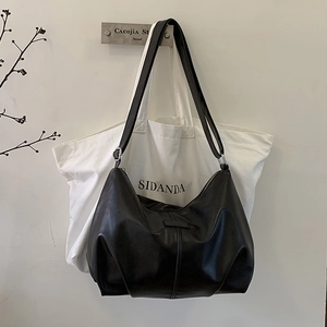 Detail of minimalist black matte leather dumpling bag with slender shoulder strap texture