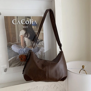 Detail of dark brown matte PU leather hobo bag with adjustable strap and bear charm