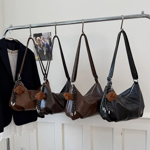Detailed comparison of four leather dumpling bags in various earth tones with charms