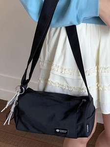 Waterproof black nylon cylinder shoulder bag for women with adjustable strap and charm