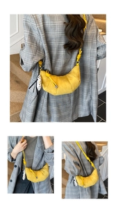 Detailed view of yellow suede crescent bag with knotted strap and polka dot accessory