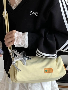 Light yellow canvas crossbody pillow bag with silver star charm and adjustable strap