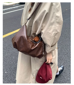 Street style view of deep brown dumpling bag with plush bear charm and decorative cord