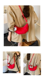 Detail of red suede crescent bag featuring knot strap and polka dot scarf accessory