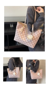 Detail of pink and white checkered tote bag featuring a white pompom and long shoulder strap