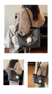 Detail view of large plaid tote bag with elegant gold logo and cute sheep charm decoration