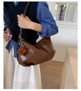 Detail of soft leather shoulder bag in dark coffee with cute plush dog pendant
