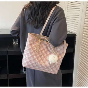 Detail of pink and white checkered tote bag featuring a soft white plush ball charm