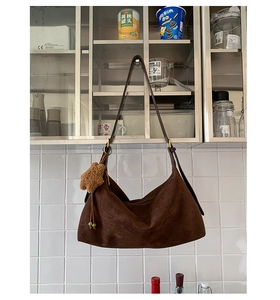 Detail of dark brown matte baguette bag with teddy bear charm and adjustable strap