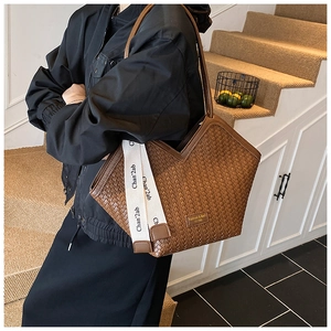 Detail of vintage brown woven tote bag featuring V-cut top and lettered strap on model