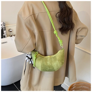 Close-up of green suede crescent bag with knot strap and cute puppy charm detail