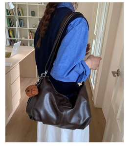Deep brown large hobo bag in soft leather with a plush bear charm on female model